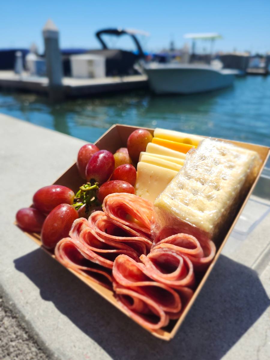 A charcuterie box on the dock with boats behind it