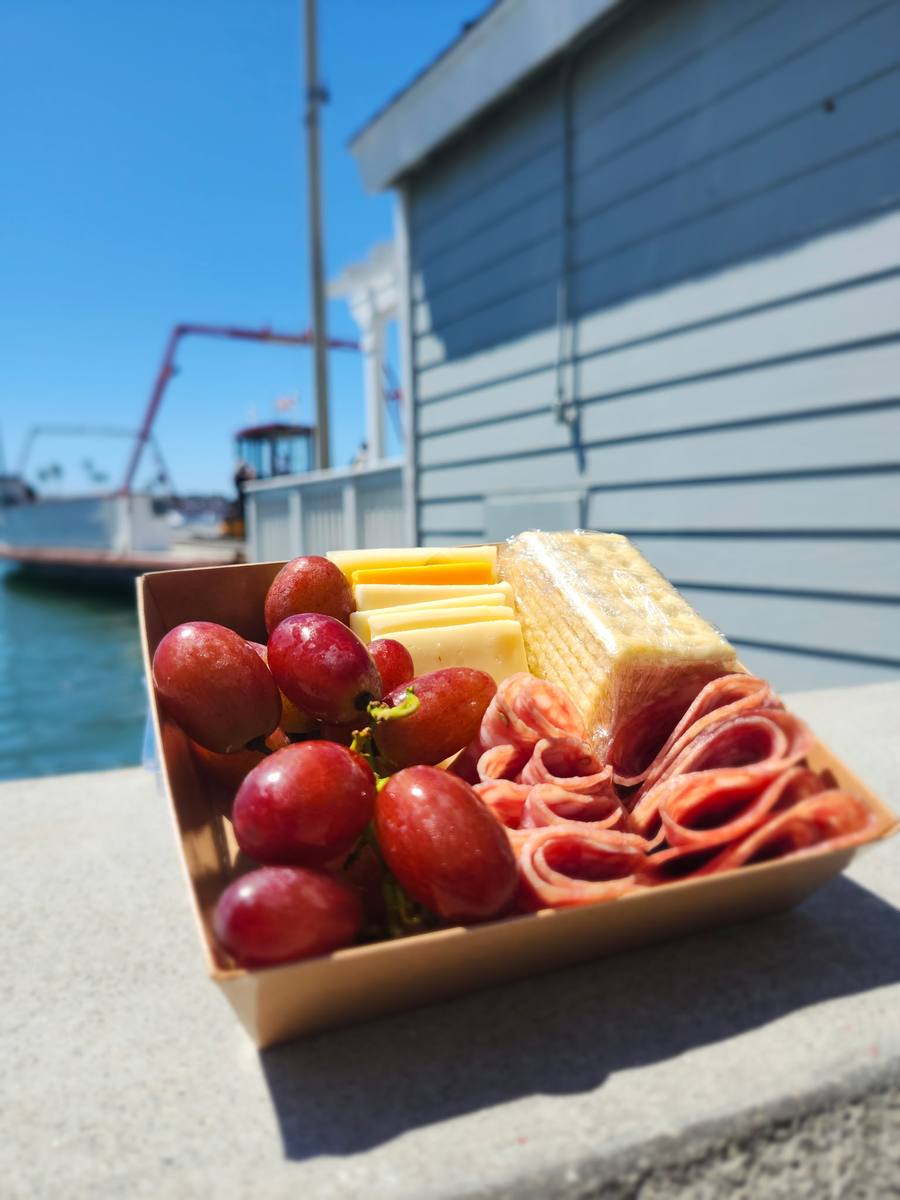 A charcuterie box resting on a dock ledge at the harbor