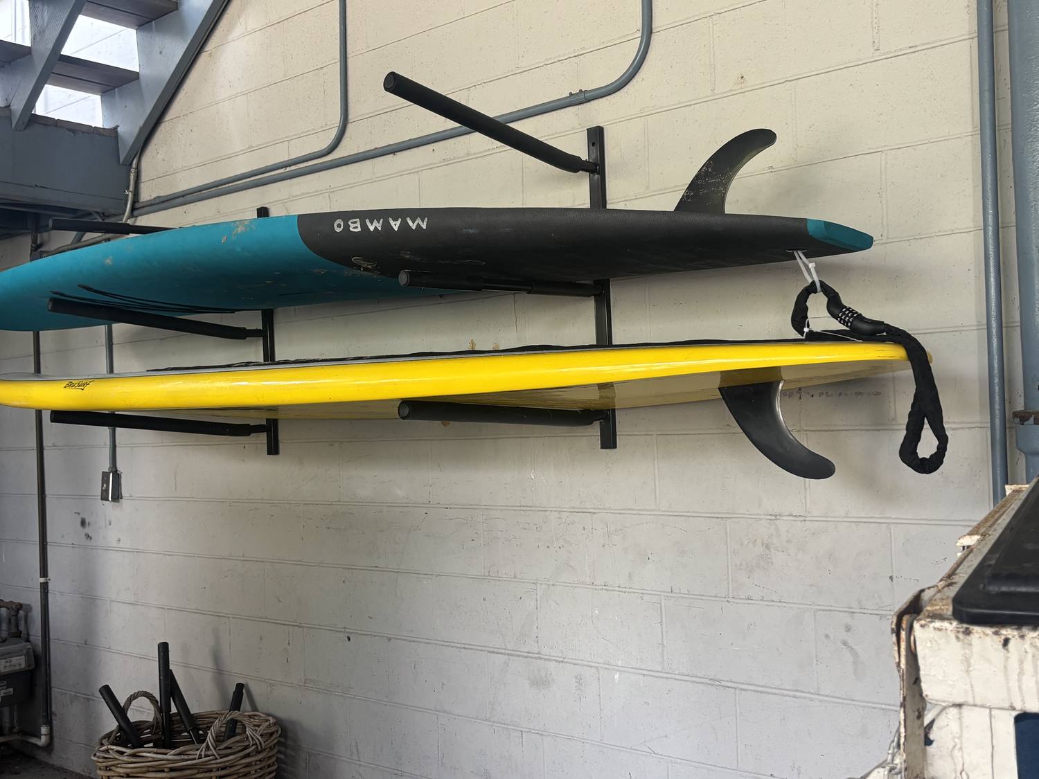 Paddleboards and a surfboard racked and ready to rent